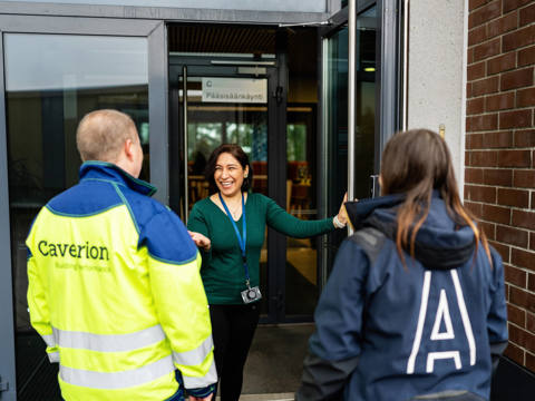 Two people entering an office, welcomed by a third person